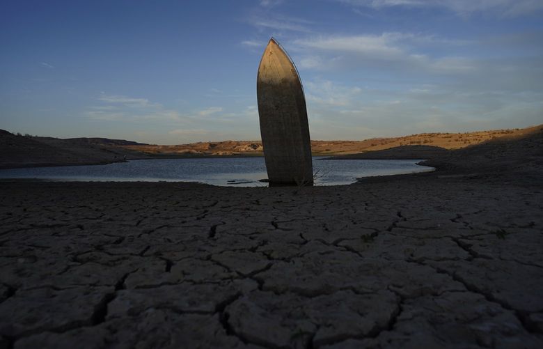 A formerly sunken boat sits upright into the air with its stern stuck in the mud along the shoreline of Lake Mead at the Lake Mead National Recreation Area, Friday, June 10, 2022, near Boulder City, Nev. Lake Mead water has dropped to levels it hasn’t been since the lake initially filled over 80 years ago. (AP Photo/John Locher) NVJL105 NVJL105