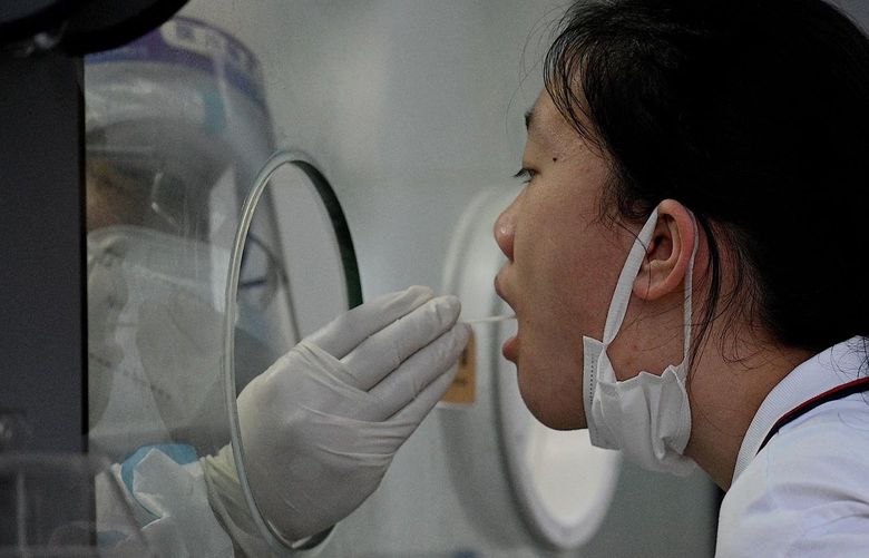 A health worker takes a swab sample from a woman to test for COVID-19 in Beijing on Tuesday, June 21, 2022. (Noel Celis/AFP/Getty Images/TNS) 51178590W 51178590W