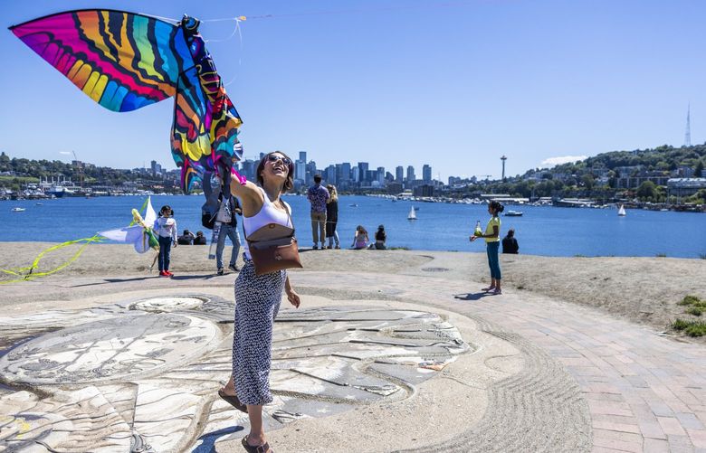 Michelle Coon helps her nephews (not pictured) fly a colorful kite at Gas Works Park during a sunny day on Thursday June 23, 2022. Her nephews flew from Chicago to visit their aunt in Seattle.
