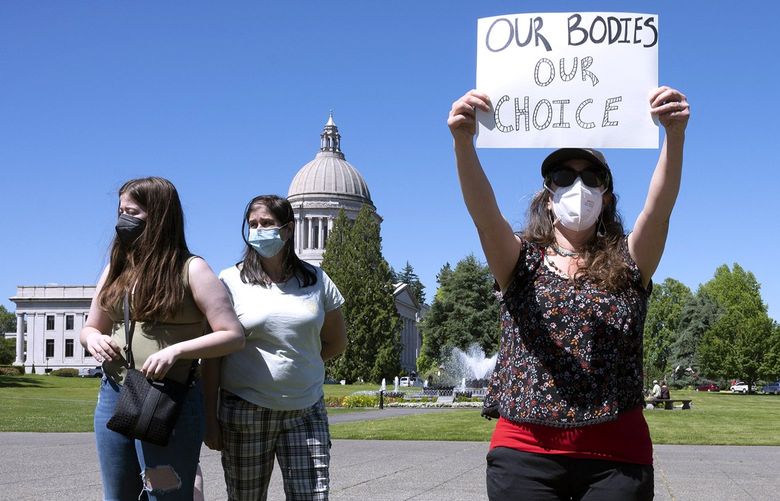 Women’s rights supporters, from left, Lacy Nadeau, Carolyn Nadeau, Rebecca Rutzick and Joe Ward, all of Olympia, Wash., rally on the Capitol Campus in Olympia, Wash., Friday, June 24, 2022, following the morning’s announcement of the U.S. Supreme Court’s overturning of Roe v Wade. (Tony Overman/The News Tribune via AP) WATAC103 WATAC103