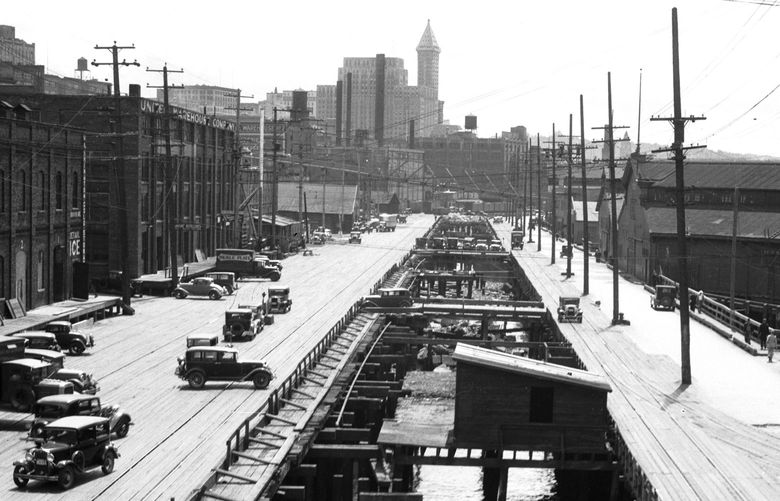 THEN1: Taken from a Lenora Street overpass that was removed in 1983, this view looks south along the timber trestle of then-Railroad Avenue on June 22, 1934. The Smith Tower presides at distant center. Credit: Seattle Municipal Archives