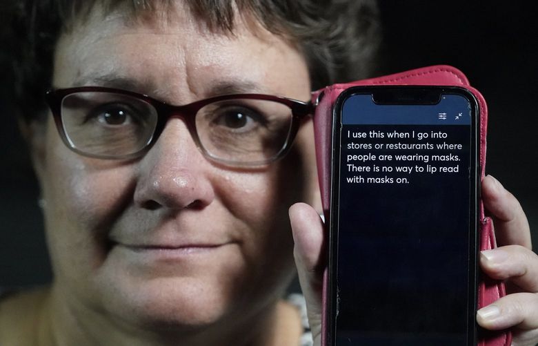 Chelle Wyatt uses her cell phone with the Otter app Friday, April 15, 2022, in Salt Lake City. People with hearing loss have adopted technology to navigate the world, especially as hearing aids are expensive and inaccessible to many.  (AP Photo/Rick Bowmer) 