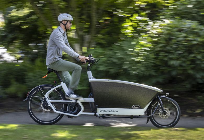 Tyler Boucher is doing most of his errands on an electric cargo bike and estimates that his two-car family buys only one tank of gas per month.  (Steve Ringman / The Seattle Times)