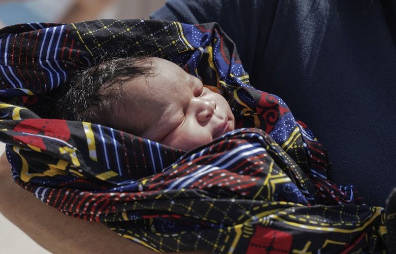 A paramedic holds a newborn boy at Mytilene port, on the northeastern Aegean Sea island of Lesbos, Greece, Wednesday, June 22, 2022. Authorities in Greece say a woman from Eritrea has given birth on an uninhabited rocky islet after traveling from nearby Turkey with other migrants. A coast guard official said 30 adult Eritreans â€’ 25 men and five women â€’ were spotted during a patrol near Lesbos. (AP Photo/Panagiotis Balaskas) XTS102 XTS102