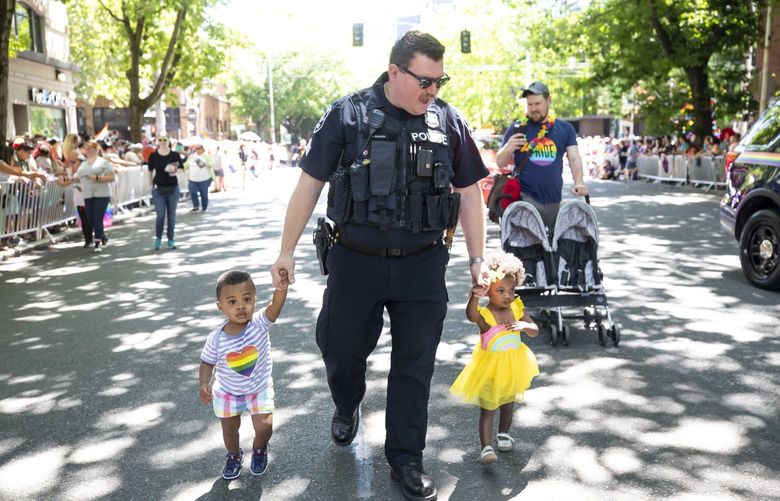 Seattle Police Sergeant Doug Raguso walks his two children in the 45th annual Seattle Pride Parade Sunday June 30, 2019. His husband, Tom Hove, pushes their stroller to the right.  210726
