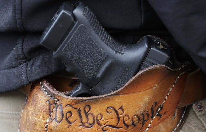 FILE – An attendee at a gun rights rally open carries his gun in a holster that reads “We the People” from the Preamble to the United States Constitution, Friday, Jan. 18, 2019, at the Capitol in Olympia, Wash. After a gunman killed 19 children and two teachers at an elementary school in Uvalde, Texas, on May 24, 2022, several pastors and rabbis around the country have challenged their conservative counterparts with this question: Are you pro-life if you are pro-guns?  (AP Photo/Ted S. Warren, File)