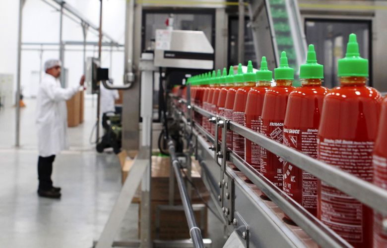 Bottles of fresh Sriracha chili sauce on a conveyor belt at the Huy Fong Foods factory in Irwindale, Calif., April 28, 2014. The city of Irwindale has moved to close down Tran’s factory unless he finds a way to more completely control the odor and irritant effects of grinding chilies on people living in nearby neighborhoods. (Emily Berl/The New York Times)