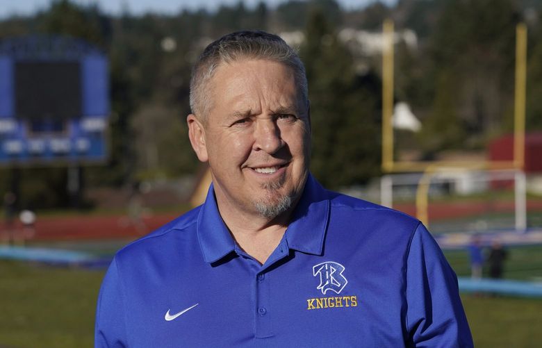 FILE – Joe Kennedy, a former assistant football coach at Bremerton High School in Bremerton, Wash., poses for a photo March 9, 2022, at the school’s football field.  The Supreme Court has sided with a football coach from Washington state who sought to kneel and pray on the field after games. The court ruled 6-3 along ideological lines for the coach. The justices said Monday the coach’s prayer was protected by the First Amendment. (AP Photo/Ted S. Warren, File) WX101 WX101