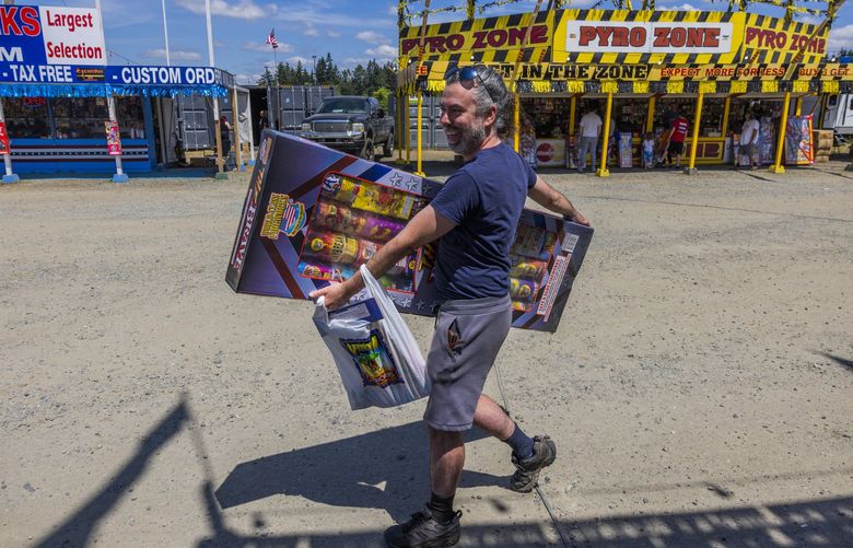 Phillip Kezele walks hands full with fireworks at the fireworks mall at the Muckleshoot Reservation on June 30, 2022. Spending about $170, Kezele said that he spent more than he wanted to on fireworks this year.