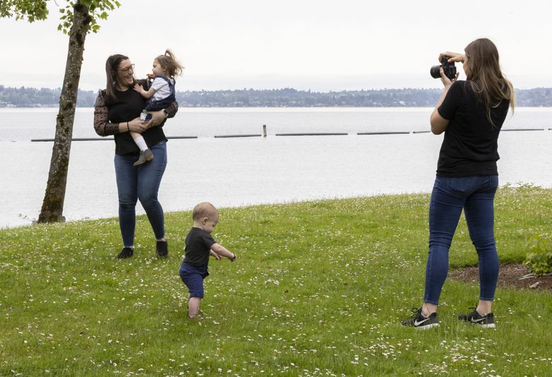 The Seattle area is in for a cloudy July 4 weekend, possibly with some rain. Above, cloudy skies cover Gene Coulon Park in Renton as 11-month-old Harrison and his mom, Bonney Chaney of Maple Valley, pose with Lenora, 2 1/2, for photographer Erin Hedin in June. (Ellen M. Banner / The Seattle TImes)