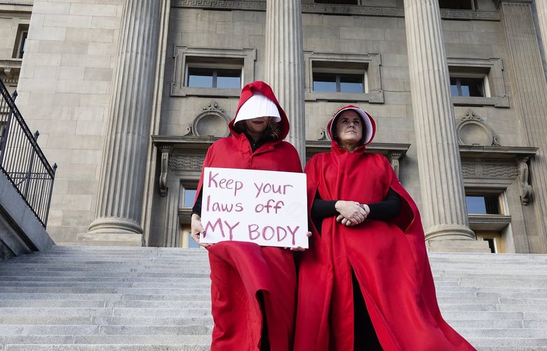 FILE – Two people stand on the steps of the Idaho State Capitol Building, during a protest, in downtown Boise, Idaho on May 3, 2022. The U.S. Supreme Court ruling overturning Roe v. Wade has legal advocates, prosecutors and residents of red states facing a legal morass created by decades of often conflicting anti-abortion legislation. Idaho has nearly three-dozen anti-abortion laws dating back to 1973, and Attorney General Lawrence Wasden’s office says he’s giving them all a close look to see which might be enforceable now that the U.S. Supreme Court has overturned Roe v. Wade. (Sarah A. Miller/Idaho Statesman via AP, File) IDBOI501 IDBOI501