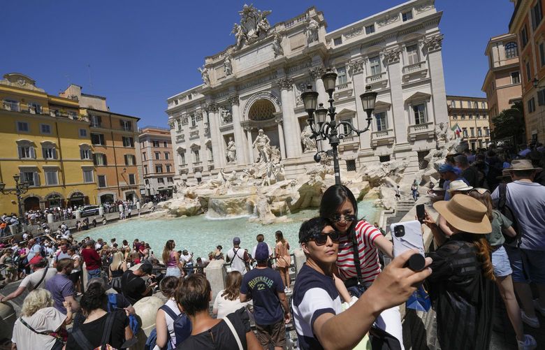 Tourists take a selfie in front of the Trevi Fountain, in Rome, Monday, June 20, 2022. Summer travel is underway across the globe, but a full recovery from two years of coronavirus could last as long as the pandemic itself. In Italy, tourists â€” especially from the U.S. â€” returned this year in droves. (AP Photo/Andrew Medichini) CER901 CER901