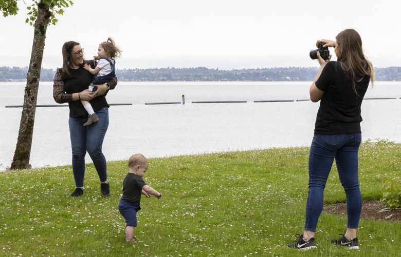 Eleven-month-old Harrison doesnâ€™t seem to interested as his mom, Bonney Chaney of Maple Valley poses with Lenora, 2 1/2, for photographer Erin Hedin of Erin Hedin Photography at Gene Coulon Park in Renton Wednesday, June 15, 2022.  There was a slight break from rain Wednesday, but later in the afternoon there is a 100% chance of more.  Thursday is expected to be dry and showers return on Friday. 220713
