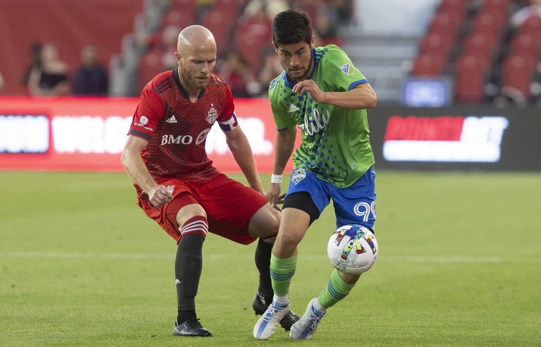 Seattle Sounders midfielder Dylan Teves, right, takes the ball away from Toronto FC midfielder Michael Bradley during second-half MLS soccer match action in Toronto, Saturday July 2, 2022. (Chris Young/The Canadian Press via AP) CHY105 CHY105