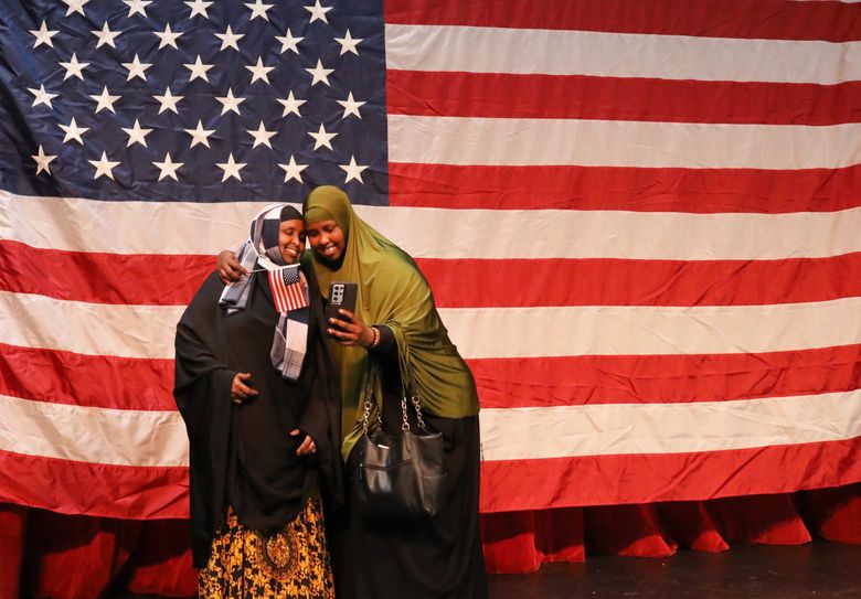 New citizen Badra Hirsi from Somalia photographs herself and her cousin Hodo Mohamed in front of the giant Stars and Stripes in the Seattle Center Armory.  At the 37th naturalization ceremony at Seattle Center, 293 people from 74 countries became citizens.  Her cousin is already a citizen.
(Alan Berner / The Seattle Times)