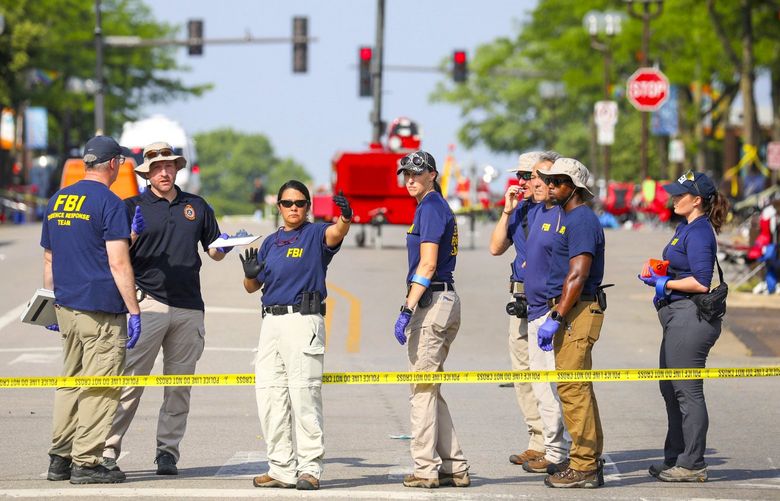 Law enforcement and members of the FBI Evidence Response team meet and gather data along Central Avenue following yesterday’s mass shooting on Tuesday, July 5, 2022 in Highland Park, Ill. (Stacey Wescott/Chicago Tribune via AP) ILCHT210