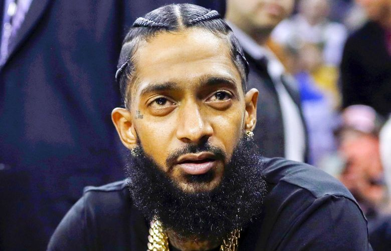 FILE – This March 29, 2018 file photo shows rapper Nipsey Hussle at an NBA basketball game between the Golden State Warriors and the Milwaukee Bucks in Oakland, Calif. Hussle was shot and killed Sunday, March 31, 2019 outside of his clothing store in Los Angeles. (AP Photo/Marcio Jose Sanchez, File) NYET222