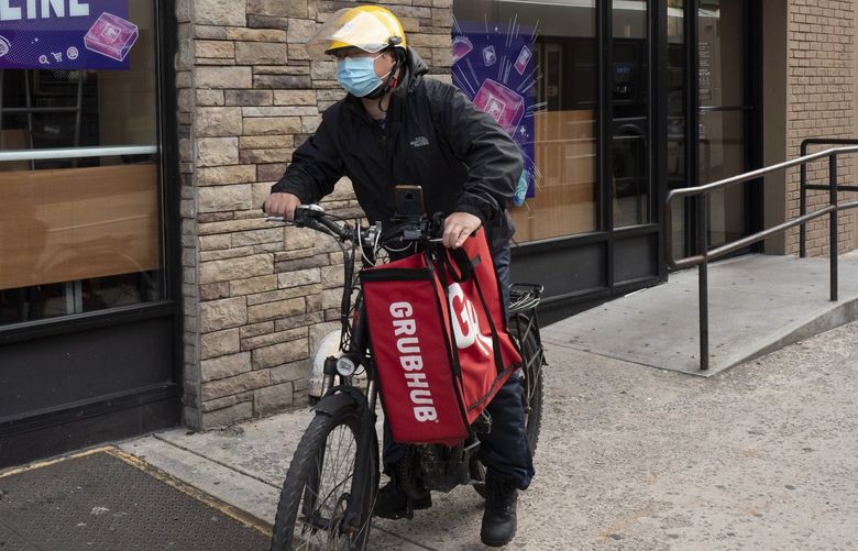 A delivery man bikes with a food bag from Grubhub, Wednesday, April 21, 2021 in New York. (AP Photo/Mark Lennihan)