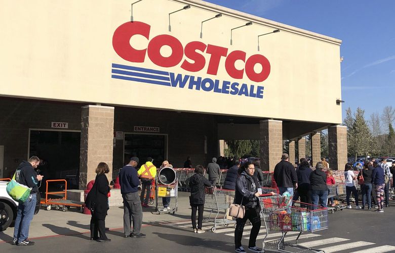 A shopper leaves as others line up to enter a Costco store, Friday, March 20, 2020, in Tacoma. (AP Photo/Ted S. Warren) 