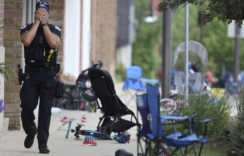 CORRECTS TO A LAKE FOREST POLICE OFFICER, INSTEAD OF LAKE COUNTY A Lake Forest, Ill., police officer walks down Central Ave in Highland Park, Ill., on Monday, July 4, 2022, after a shooter fired on the northern suburb’s Fourth of July parade. (Brian Cassella/Chicago Tribune via AP)