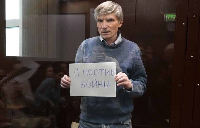 Alexei Gorinov holds a sign “I am against the war” standing in a cage during hearing in the courtroom in Moscow, Russia, Tuesday, June 21, 2022. Moscow’s Meshchansky District Court ruled Tuesday that Alexei Gorinov, a member of the municipal council in one of Moscow’s districts, should stay in custody pending his trial on charges of discrediting the country’s armed forces. (AP Photo/Alexander Zemlianichenko) XAZ111 XAZ111