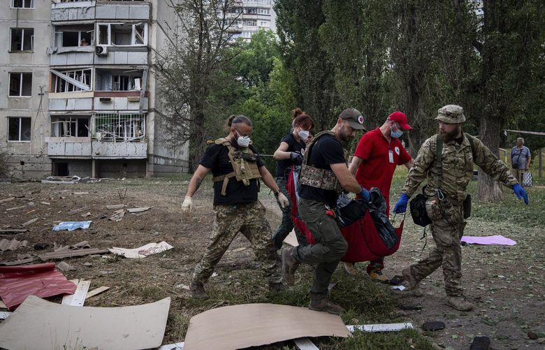 Paramedics carry the body of a woman who was killed during a Russian bombardment at a residential neighborhood in Kharkiv, Ukraine, on Thursday, July 7, 2022. (AP Photo/Evgeniy Maloletka) XSG111 XSG111