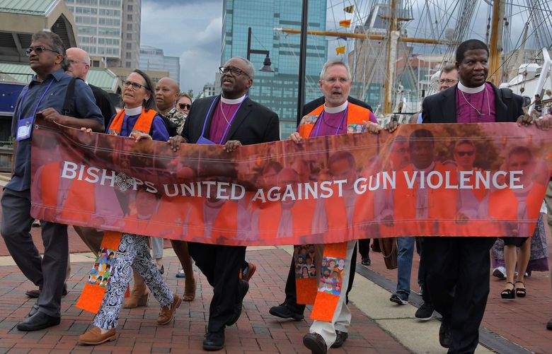 Episcopal bishops lead a procession Friday along the Baltimore waterfront toward a prayer vigil, close to a scene where a driver who swung a bat at squeegee workers was shot to death. (Karl Merton Ferron/The Baltimore Sun/TNS) 52804345W 52804345W