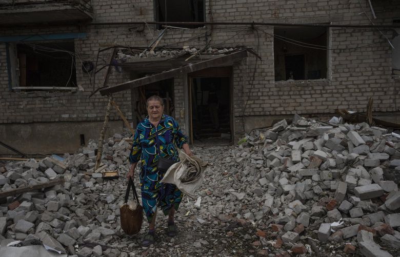 A woman salvages what she can from her home, after a rocket hit an apartment residential block, in Chasiv Yar, Donetsk region, eastern Ukraine, Sunday, July 10, 2022. At least 15 people were killed and more than 20 people may still be trapped in the rubble, officials said Sunday. (AP Photo/Nariman El-Mofty) NM118 NM118