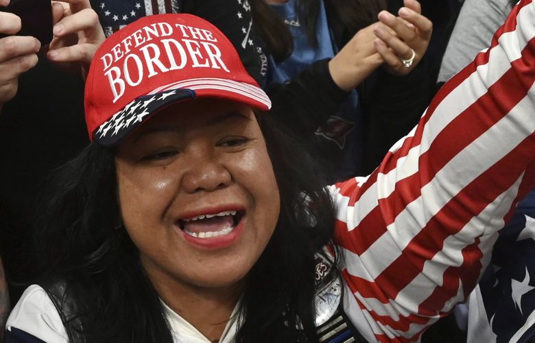 Mimi Israelah, center, cheers for Donald Trump inside the Alaska Airlines Center in Anchorage, Alaska, during a rally Saturday July 9, 2022. An investigation has been launched after a person believed to be an Anchorage, Alaska, police officer was shown in a photo with Israelah flashing a novelty “White Privilege card.†The social media post caused concerns about racial equality in Alaska’s largest city. (Bill Roth/Anchorage Daily News via AP) AKAND601 AKAND601