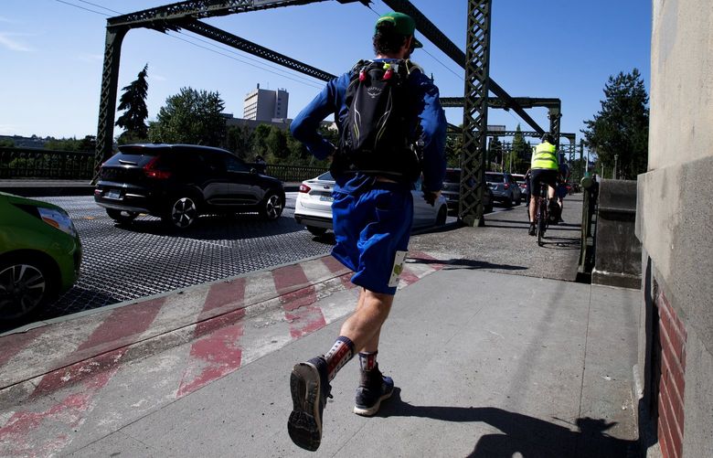 Crossing the Mountlake Bridge, Greg Nance puts on the afterburners after losing time near Redmond due to a television news interview, Wednesday, July 13, 2022, in Seattle, while working on a 3,000-plus-mile run from the East Coast to the West to amplify awareness about youth mental health. Nance heads toward Pier 62 where he met with family, friends and supporters.