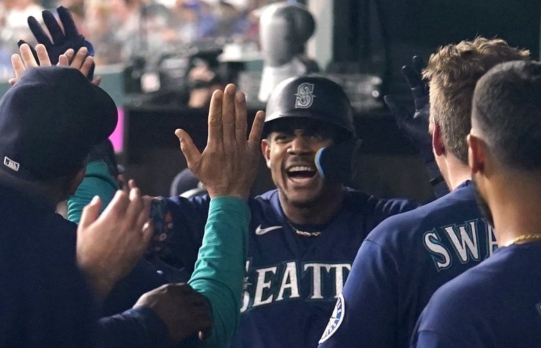 Seattle Mariners’ Julio Rodriguez, center, celebrates in the dugout after Rodriguez hit a grand slam in the eighth inning of the team’s baseball game against the Texas Rangers, Friday, July 15, 2022, in Arlington, Texas. (AP Photo/Tony Gutierrez) TXTG120 TXTG120