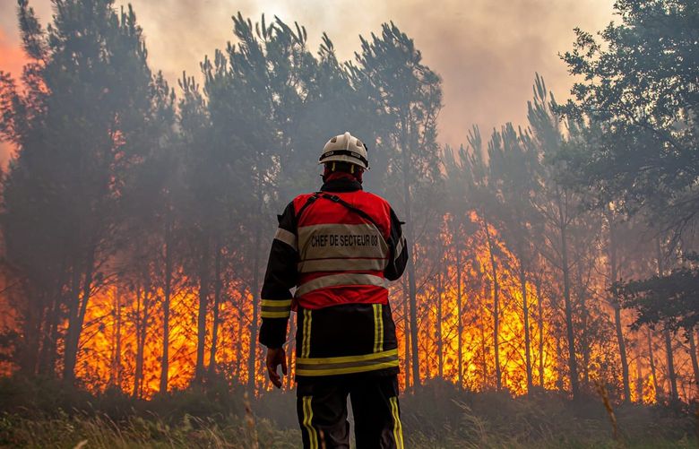 This photo provided by the fire brigade of the Gironde region (SDIS 33) shows a firefighter fighting a wildfire near Landiras, southwestern France, Saturday July 16, 2022 . Strong winds and hot, dry weather are frustrating French firefighters’ efforts to contain a huge wildfire that raced across pine forests in the Bordeaux region Saturday for a fifth straight day, one of several scorching Europe in recent days. (SDIS 33 via AP) ENA103 ENA103