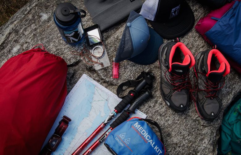 Hiking safety gear, including a tent, footwear, a headlamp, a compass, a lighter, a map, hiking poles and a water bottle, is pictured at the Seattle branch of the Mountaineers, a nonprofit organization focused on outdoor activities, on July 18, 2022.