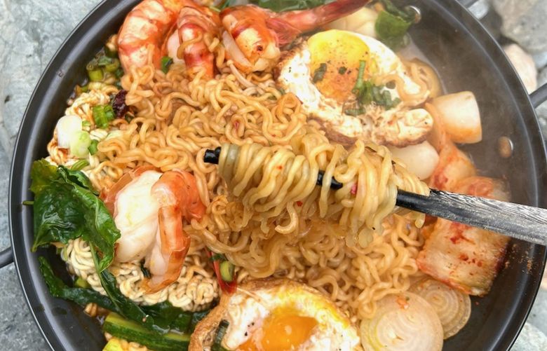 During a family hike, Seattle chef Danna Hwang prepares a steaming pot of ramen noodle soup on the trail. She prepares many ingredients ahead of time at home, including mushrooms, greens, onions, shrimp, scallops and pre-fried eggs, and adds them to boiled ramen noodles she cooks on a campstove. Credit: Paul Hwang