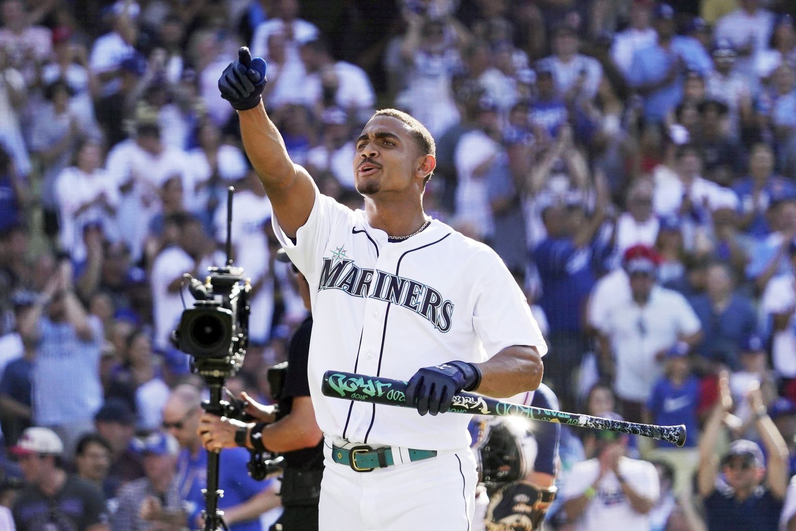 Seattle Mariners' Julio Rodriguez smiles as he speaks with a coach