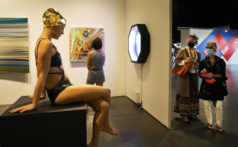 Artist Carole Feuerman’s life-size hyper-realist bather is an attention-getter at the Melissa Morgan Fine Art booth at the Seattle Art Fair Friday. The piece, created with 3-D imaging and adorned with a 24-karat gold-leaf cap, already sold for $158,000. The fair continues through Sunday at the Lumen Field Event Center. (Alan Berner / The Seattle Times)