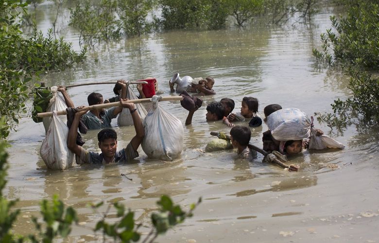 FILE- A Rohingya family reaches the Bangladesh border, Tuesday, Sept. 5, 2017, after crossing a creek of the Naf river on the border with Myanmmar, in Cox’s Bazar’s Teknaf area. Judges at the International Court of Justice rule Friday July 22, 2022, on whether a case brought by Gambia alleging that Myanmar is committing genocide against the Rohingya can go ahead. Myanmar argues that the court does not have jurisdiction. (AP Photo/Bernat Armangue, file) PDJ106 PDJ106