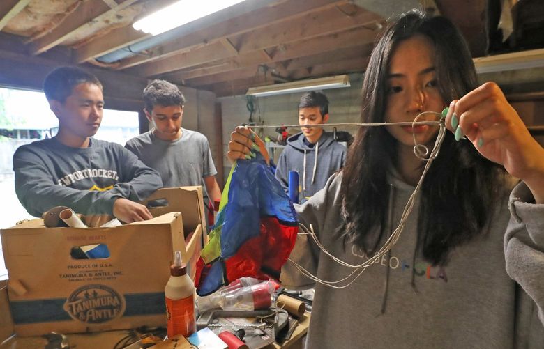 In their basement workshop, Newport High rocketry team member Rose Liu, right, prepares a parachute to be packed into one of their rockets. At left are team members Minghan Sun, Vanu Rao and Ethan Luo. The Newport High School rocketry team took home the first place prize at the National Rocketry Challenge last month, and will be heading to London, leaving Seattle late July to compete against three other countries at the international competition. The rockets are designed and built from scratch, meant to travel hundreds of feet in the air while carrying eggs — and landing without breaking them. 220789