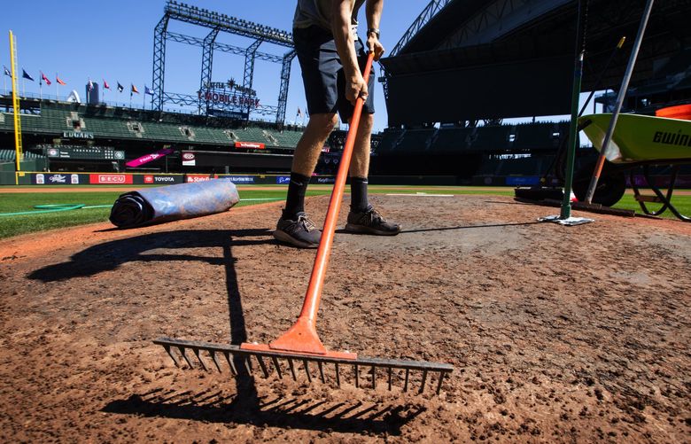 Mariners day grounds crew member Jay Herrick prepares the clay foundation on the mound Monday, July 25, 2022, in Seattle, before M’s starter Chris Flexen pitches against Texas at T-Mobile Park.