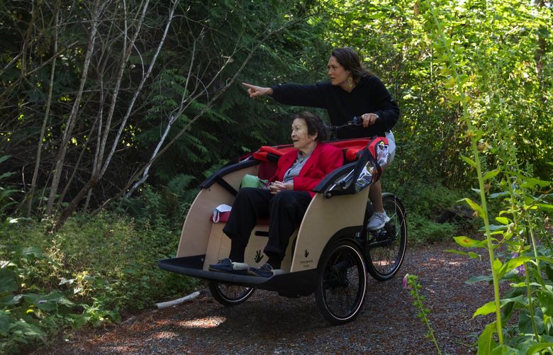 Gabrielle Myers of Cycling Without Age points out a foxglove flowering while taking Zandra Walker, 84, for a ride on a special ebike, Thursday, July 21, 2022 in Redmond.
