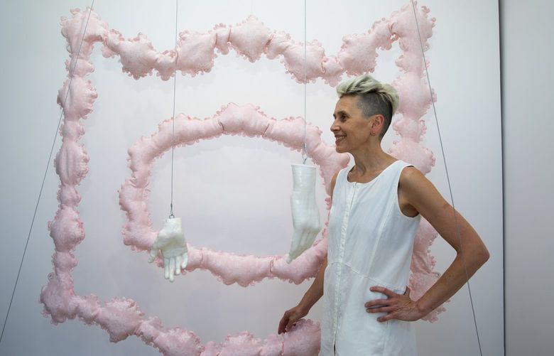 Timea Tihanyi with her artwork called “Like Love,” Tuesday, July 26, 2022 in Seattle’s Ballard neighborhood, on display at Das Schaufenster window gallery through August. Tihanyi is a Seattle-based artist who was born and grew up in Hungary.