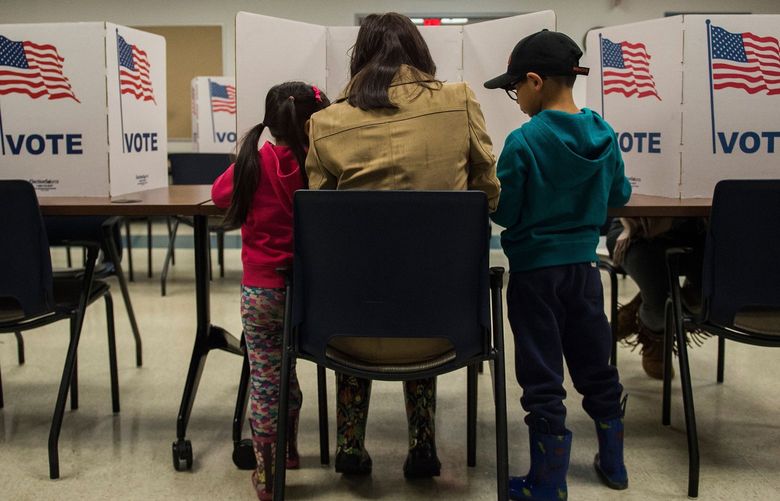 A woman and her children vote at a polling station during the mid-term elections at the Fairfax County bus garage in Lorton, Virginia. on Nov. 6, 2018. (Andrew Caballero-Reynolds/AFP/Getty Images/TNS) 54156434W 54156434W