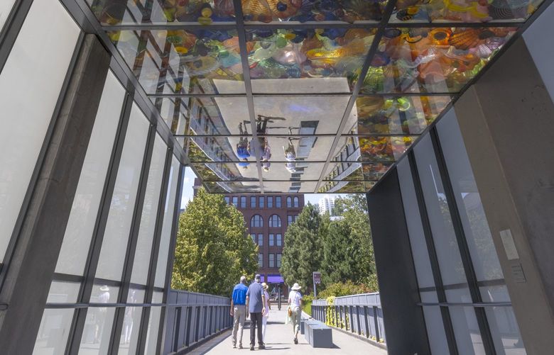 A group of people walk past Dale Chihuly’s Seaform Pavilion near the Museum of Glass in Tacoma Thursday, July 28, 2022. Temperatures are predicted to remain in the low 90’s through Sunday and will be back to the high 70’s at the beginning of the week. 221134