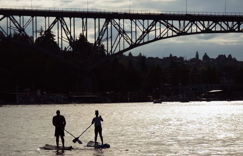 Paddleboarders head toward the Aurora Bridge on Lake Union Monday, July 4, 2022, in Seattle, Wash.