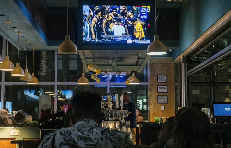 Patrons watch a basketball game at a bar in Manhattan on July 20, 2022. Sports and media executives predict that the NBA will stick with traditional broadcasters after its current agreements expire. (Hiroko Masuike/The New York Times)