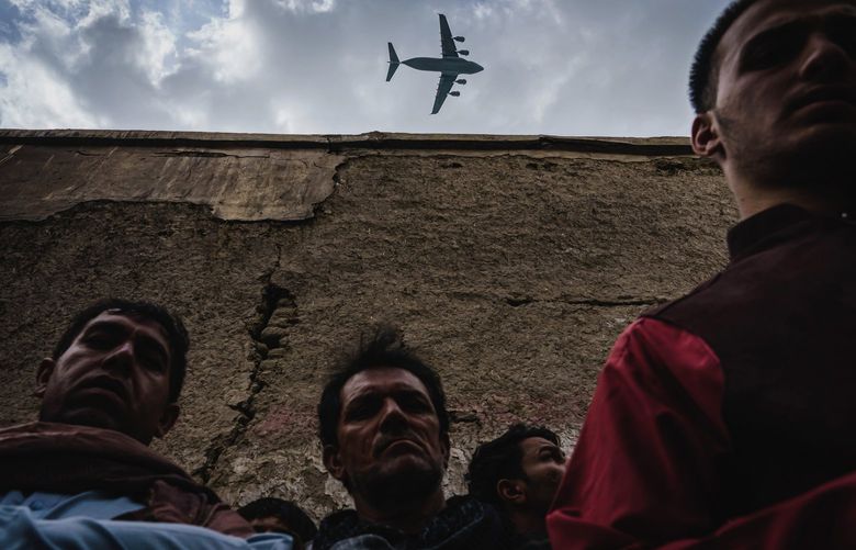 A military transport plane flies over as relatives and neighbors of the Ahmadi family mourn those who died in Kabul, Afghanistan, last August. (Marcus Yam/Los Angeles Times/TNS)
