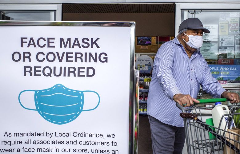 Tuesday, July 7, 2020   A customer exits a Fred Meyer store with a sign at the entrance requiring a face covering.  Starting today Washington businesses must turn you away if your’re not wearing a face covering inside the business. 214437 214437