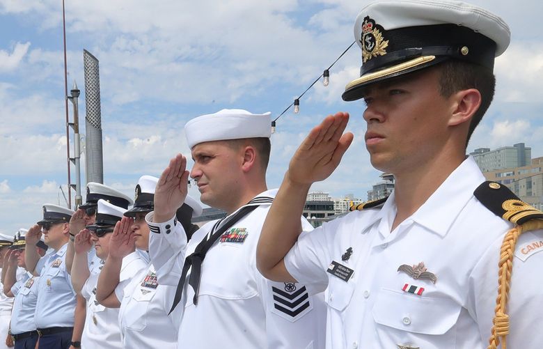 Navy officers salute ships from the U.S. Navy, U.S. Coast Guard, and Royal Canadian Navy and Coast Guard rescue helicopter. in a SeaFair Fleet Week parade in Elliott Bay, Monday, August 1, 2022.  At far right is Canadian Fleet Pacific Navy officer Lt Adrian ’thow.
LO LO LO  221142