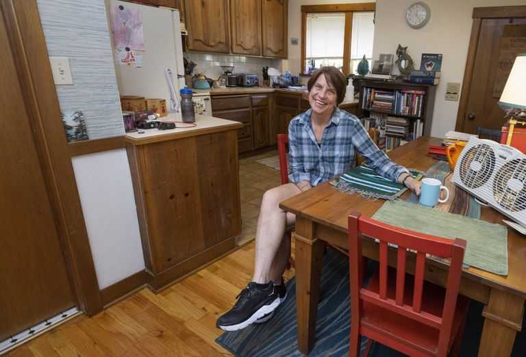 Renter sits in the dining room/kitchen area of her one-bedroom apartment near Green Lake