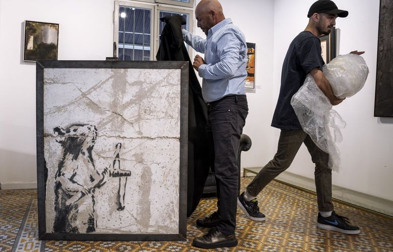 Koby Abergel, an Israeli art dealer, reveals a painting by the secretive British graffiti artist Banksy that was mysteriously transferred from the occupied West Bank to the Urban Gallery in Tel Aviv, Israel, Thursday, Aug. 4, 2022. The painting of a slingshot-toting rat once stood near Israel’s separation barrier and was one of several works created in 2007 that protest Israel’s decades-long occupation of territories the Palestinians want for a future state. (AP Photo/Oded Balilty) XOB101 XOB101